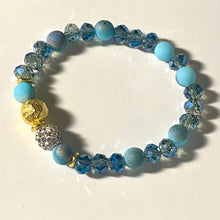 Load image into Gallery viewer, Blue Skies II - Light blue iridescent ceramic beads with dark teal blue crystals, gold disc spacers, and white crystal pavé bead
