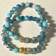 Load image into Gallery viewer, Blue Skies II - Light blue iridescent ceramic beads with dark teal blue crystals, gold disc spacers, and white crystal pavé bead
