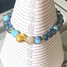 Load image into Gallery viewer, Blue Skies II - Light blue iridescent ceramic beads with dark teal blue crystals, gold disc spacers, and white crystal pavé bead
